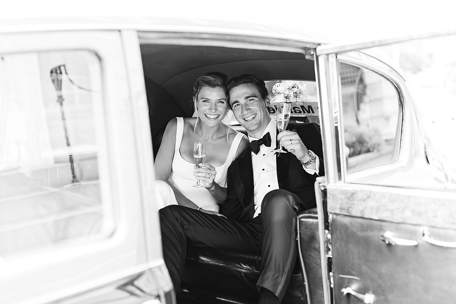 Bride and groom smile in a vintage Rolls Royce