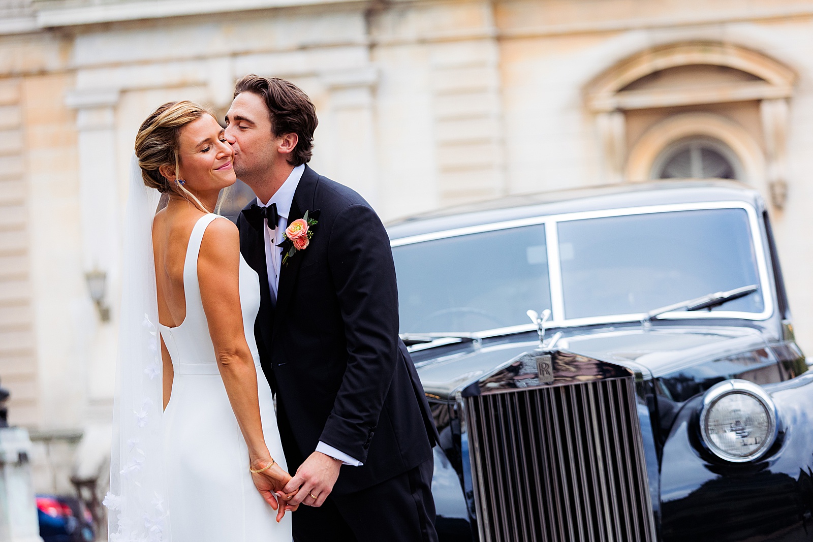 Groom kisses bride's cheek by vintage Rolls Royce