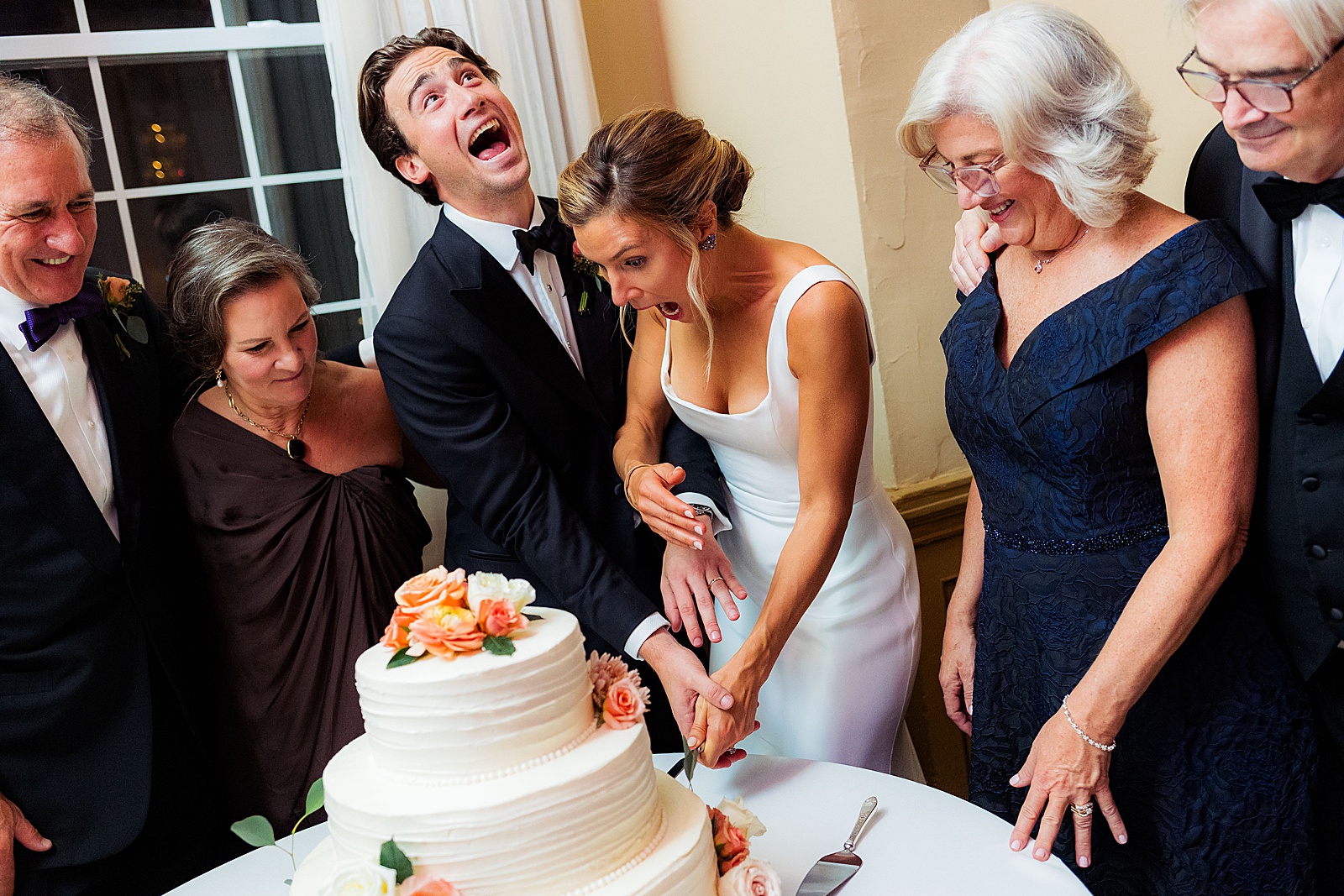 Bride and groom cut their wedding cake with silly expressions