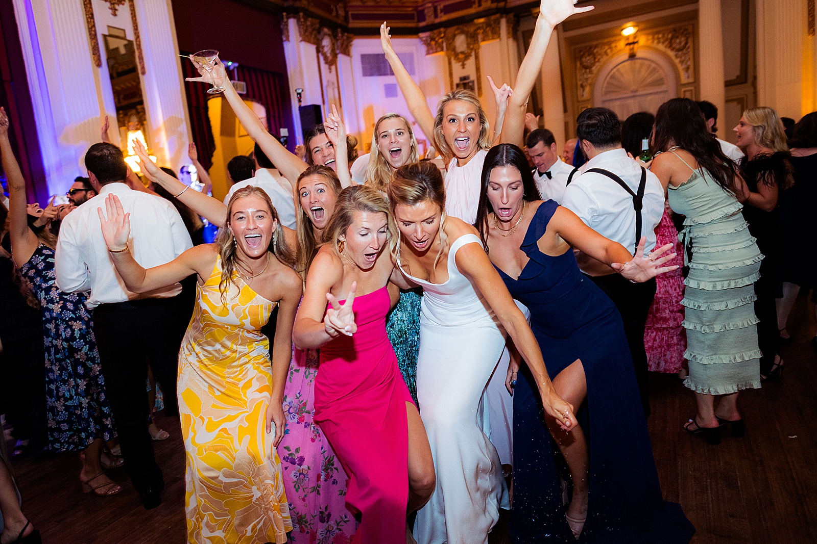 Bride and group of girlfriends drop a glass on the dance floor