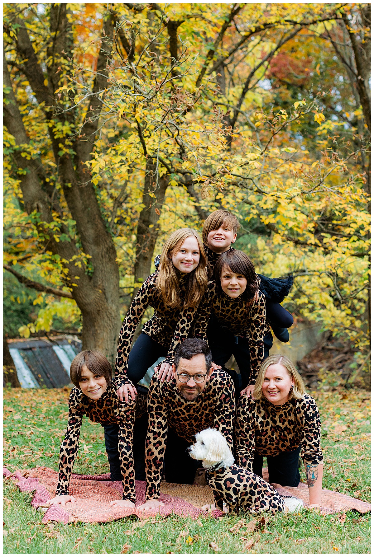 Family makes a family pyramid with everyone in matching leopard print for their awkward family photos in Baltimore.