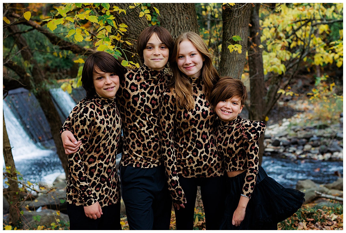 Siblings smile with matching leopard turtlenecks. 