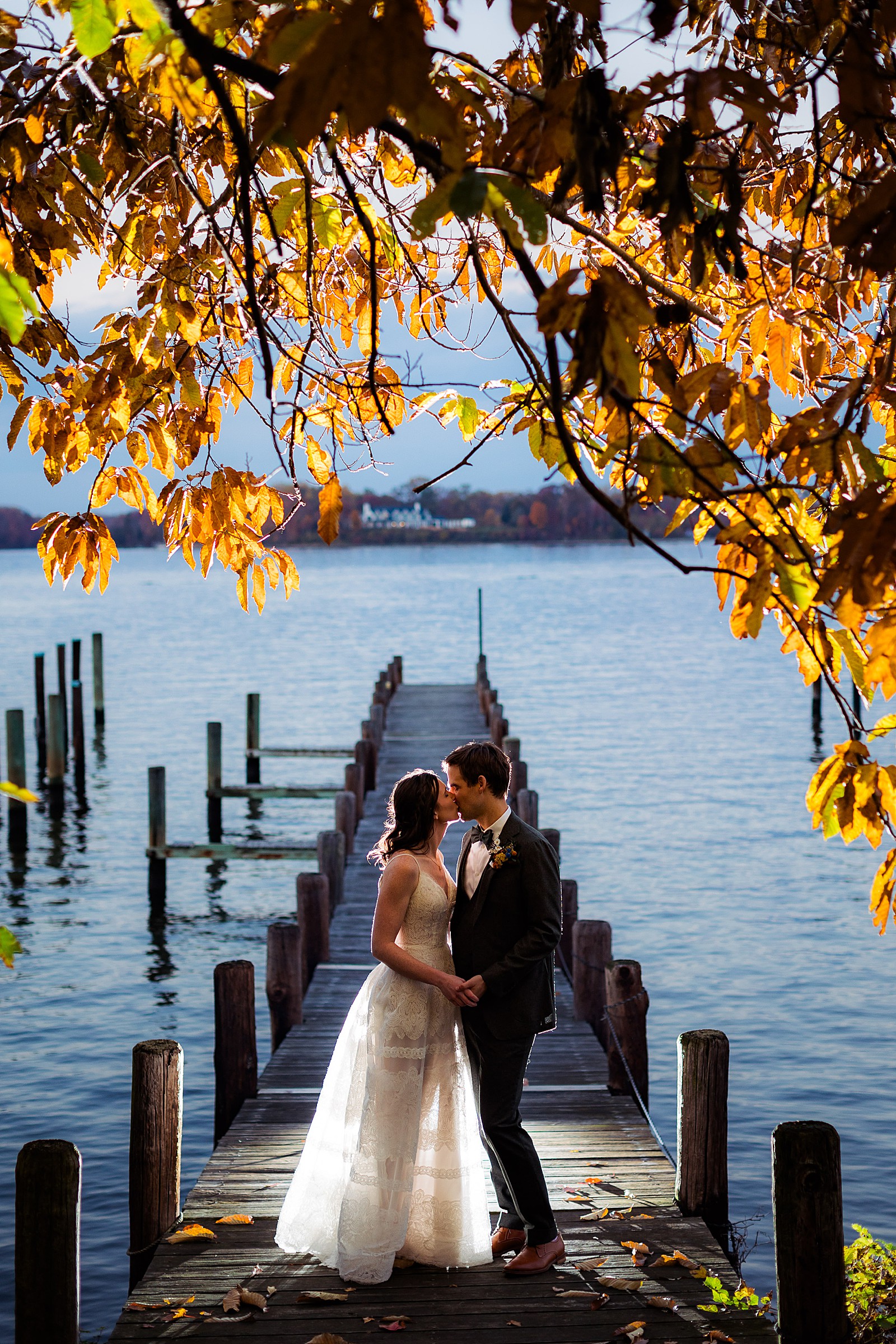 Couple kisses on the pier at their sunset fall London Town wedding photography session.