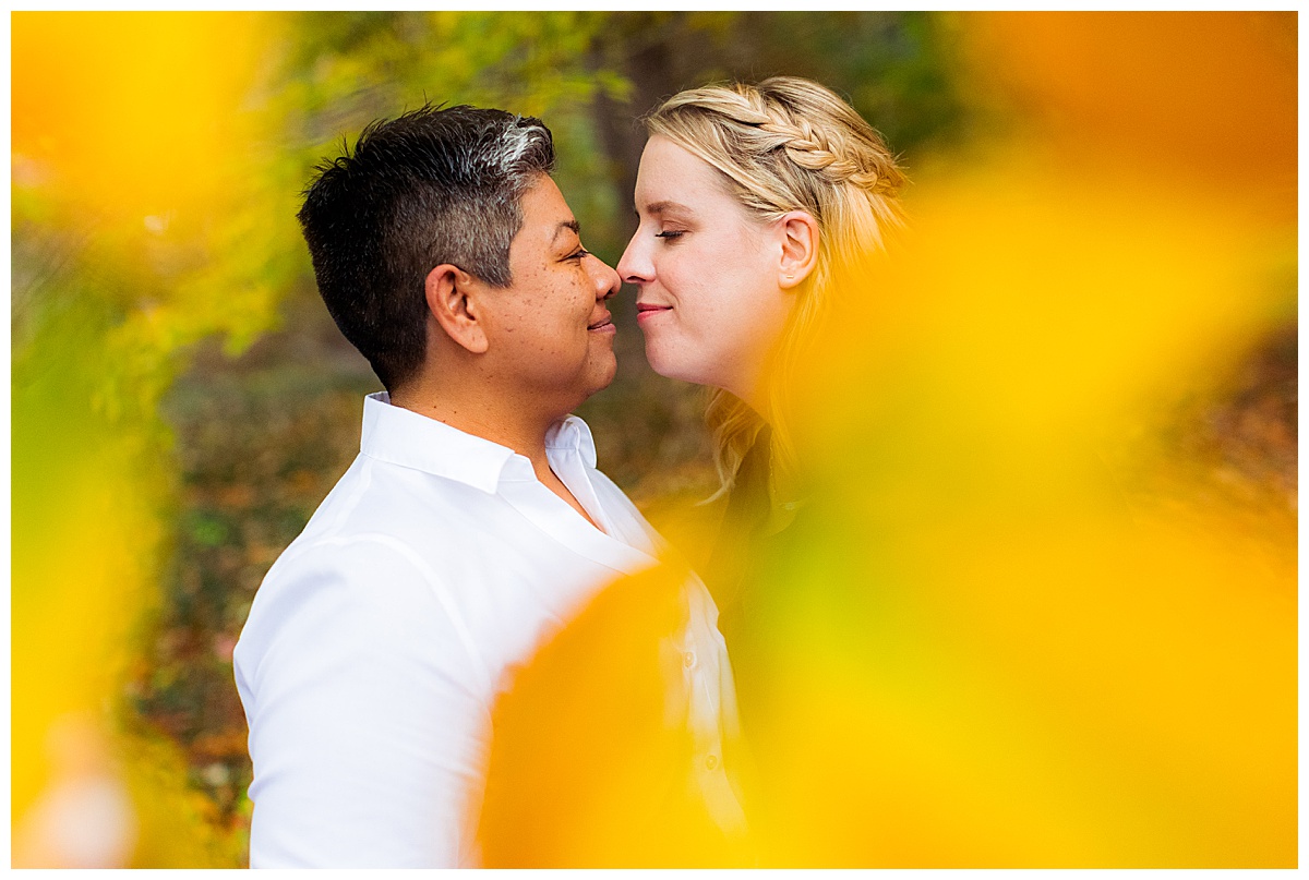 LGBTQ couple get cozy in some colorful fall leaves in Sligo Creek Park