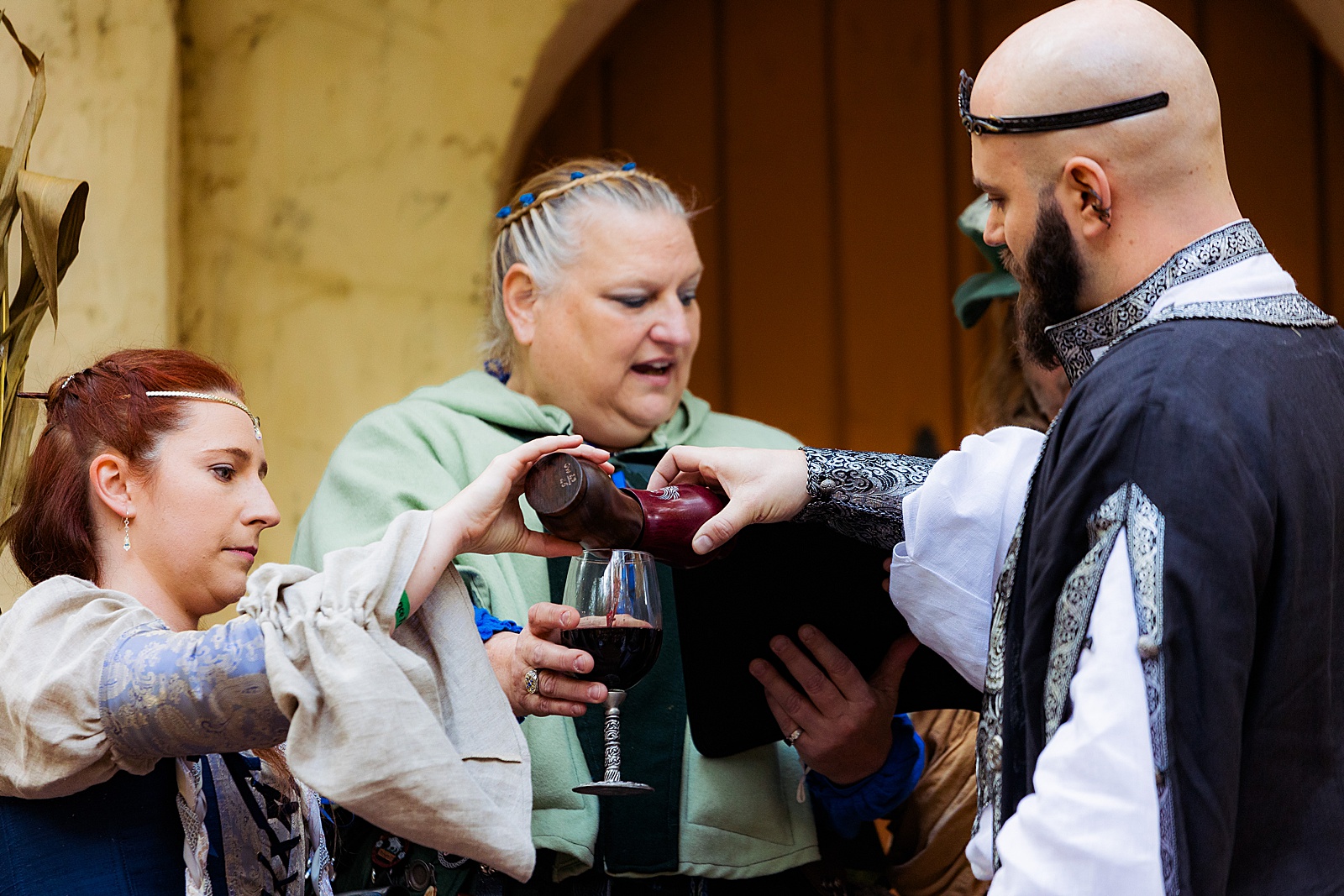 Bride and groom pour wine into a glass at a renaissance festival wedding.