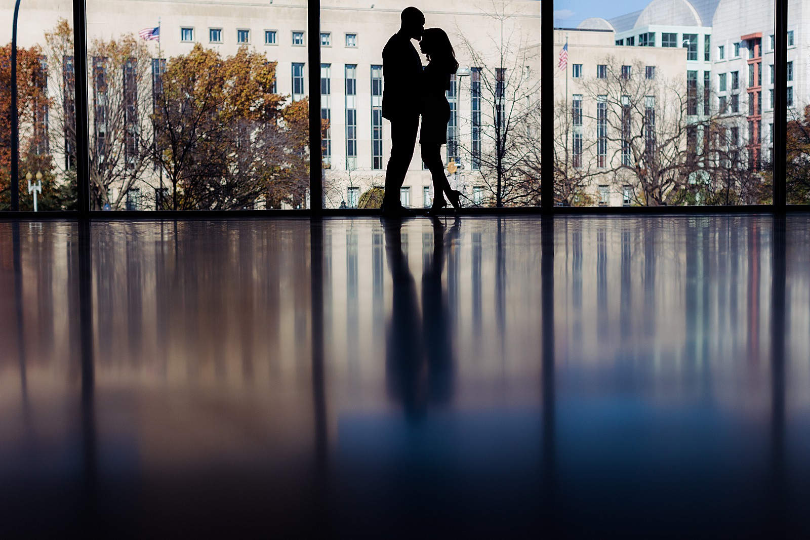 Couple is silhouetted against a cityscape at their DC National Gallery of Art engagement photography session.