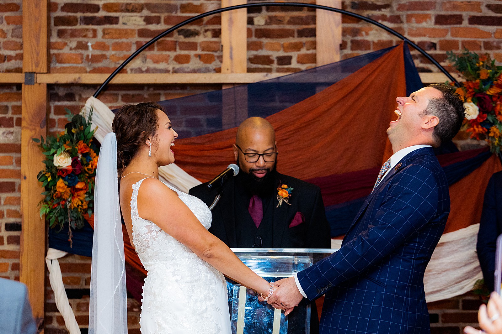 Bride and groom share a laugh during their indoor ceremony at their rainy day AVAM wedding.