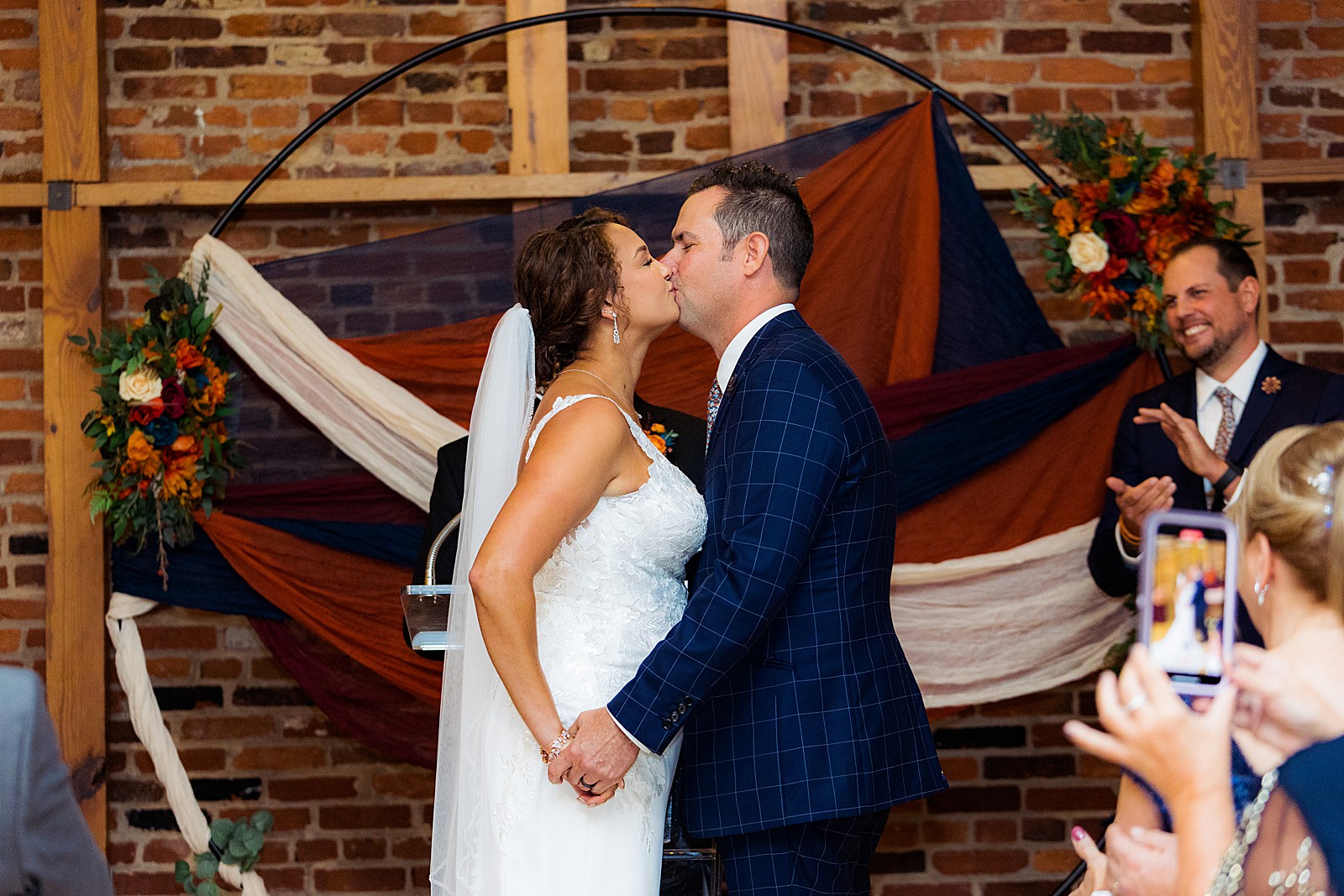 Bride and groom have their first kiss during an indoor ceremony at their rainy day AVAM wedding.