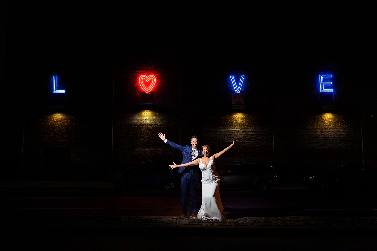 Bride and groom pose for an outdoor night shot in front of the love sign at the American Visionary Art Museum in Baltimore. 