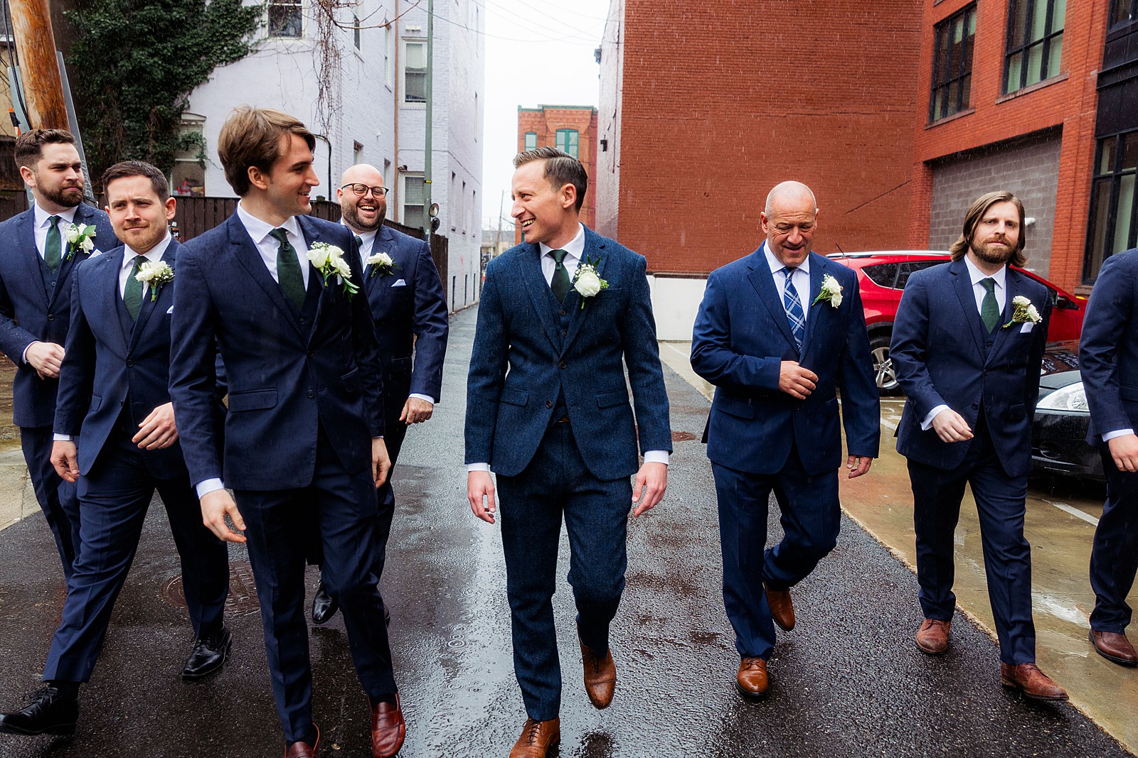 Groom and groomsmen walk to the church on a rainy spring day. 