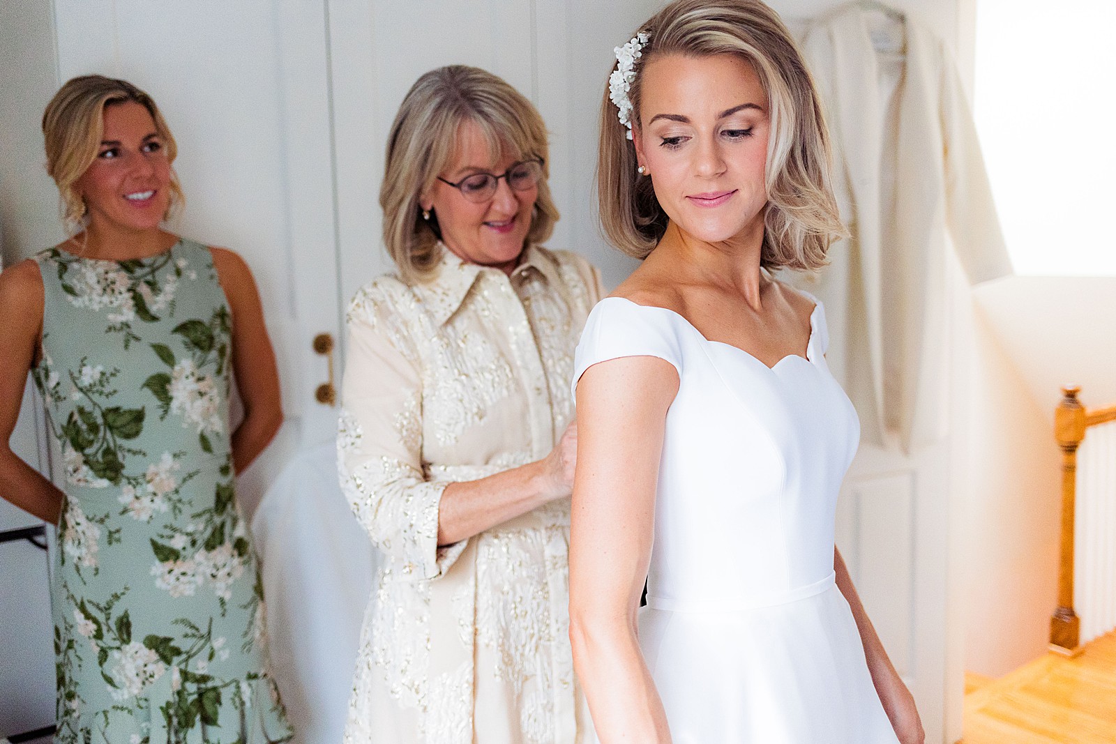 Bride's mom zips up bride's wedding dress on the day of the wedding. 