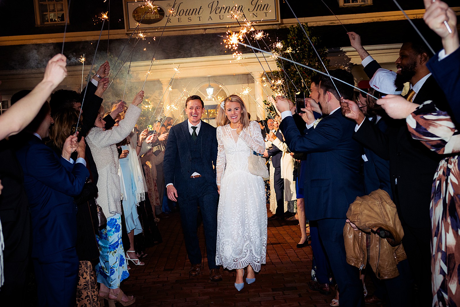 Bride and groom walk through a sparkler exit to end the night at their rainy Mount Vernon Inn Restaurant wedding.